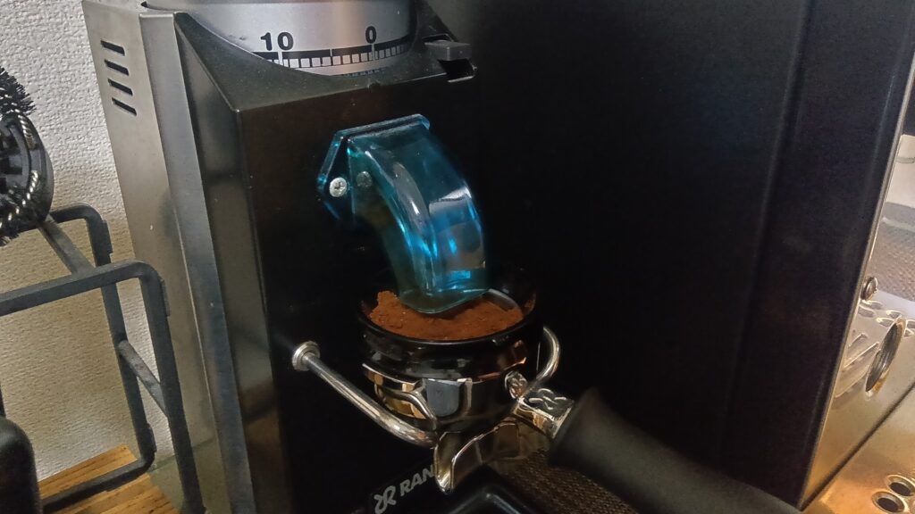 Rancilio Rocky吐出口アップ：クリックダイヤル「10」、青いシュート、ポルタフィルターに挽きたて粉が落ちる瞬間